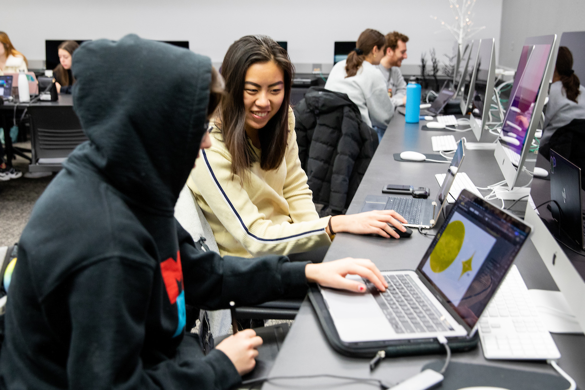 Graphic Design classroom with two students collaborating over a laptop