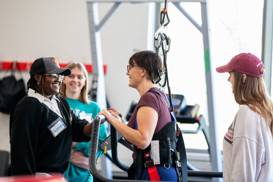 Adapted Fitness class where students are working with someone in a physical therapy harness
