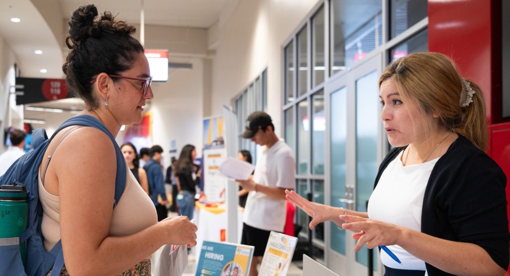 Student at vendor table speaking to employer
