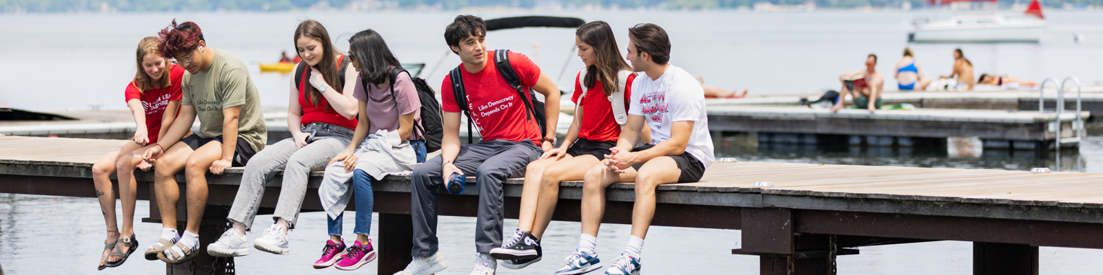 Students sitting on a pier over the lake
