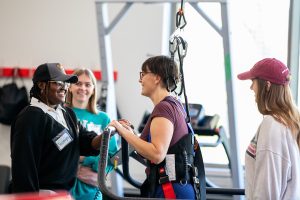 Adapted Fitness class where students are working with someone in a physical therapy harness
