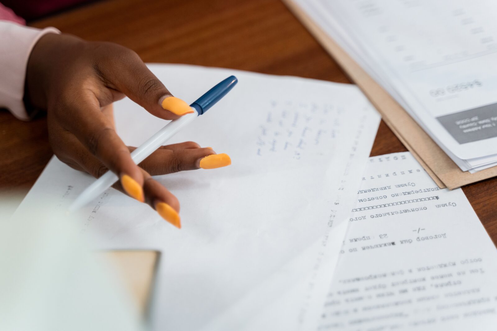 an image of a hand holding a pencil in front of papers